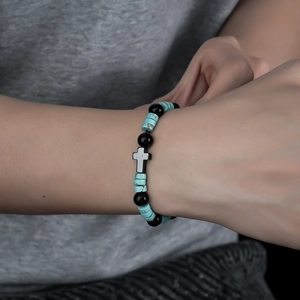 Cross bracelet featuring blue turquoise discs and black obsidian beads on a wrist
