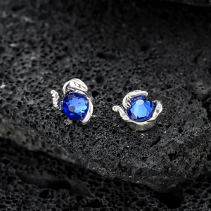 Boucles d'oreilles cygne bleu avec cristaux sur fond de roche volcanique noire