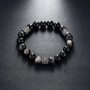Detailed view of natural silver obsidian beads and carved metal spacers on black leather