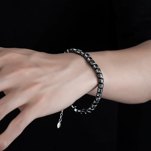 Détail d'un bracelet en hématite noire avec chaîne d'extension argentée portée au poignet