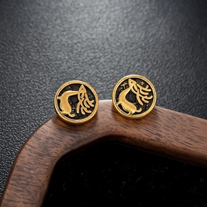 Macro detail of vintage gold elk earrings with black textured inlay on leather background