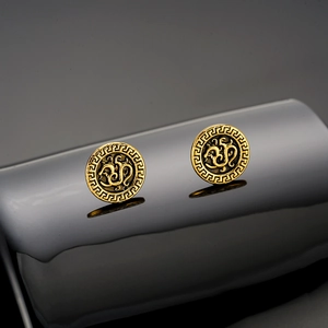 Detailed close-up of vintage gold stud earrings with Greek key patterns on a black stand