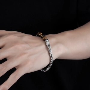Close-up of tiger eye stone beads and silver twisted stainless steel chain on a male wrist