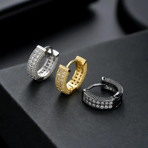 Detailed close-up of three huggie earrings in silver gold and black with zircon stones