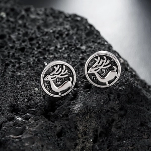 Retro silver elk stud earrings featuring embossed reindeer on a volcanic rock surface