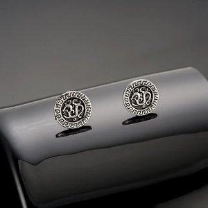 Macro detail of vintage silver studs featuring ancient rune symbols and meander patterns