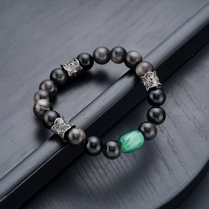 Macro detail of natural silver sheen obsidian beads with green gemstone and vintage spacer
