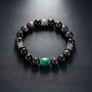 Macro detail of natural silver sheen obsidian beads with a green malachite focal bead