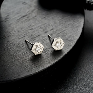 Macro shot of silver hexagonal stud earrings with sparkling cubic zirconia and sunburst texture