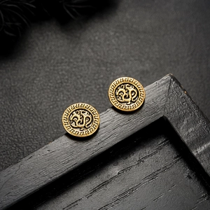 Macro detail of vintage gold rune stud earrings with greek key border on black leather