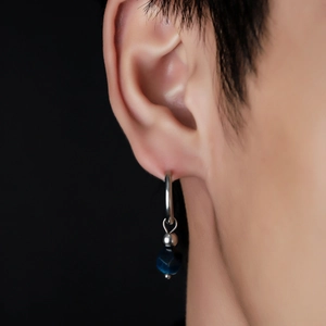 Gros plan de boucles d'oreilles créoles avec perle bleue sur fond sombre