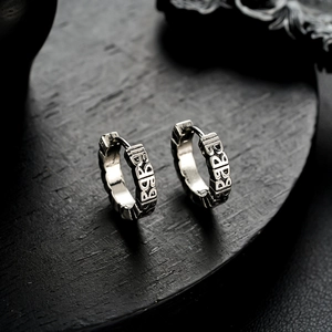 Retro silver huggie earrings with BABY relief engraving on dark wood surface