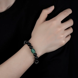 Detail of beaded bracelet with black obsidian, green oval stone and silver spacer beads