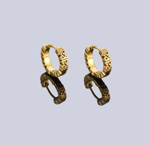 Detail of gold earrings with BABA relief carving and textured edges on mirror