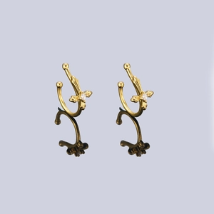 Detail view of golden cross and angel wing ear cuffs with sparkling white zircon stones