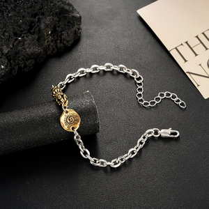 Dettaglio del ciondolo Vajra dorato e medaglia solare su bracciale a catena