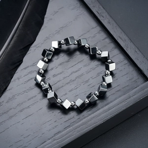 Macro detail of black hematite square beads and silver spacer beads on a textured surface