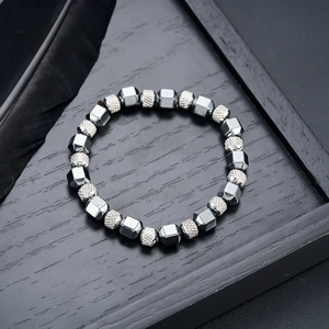 Detailed view of beaded bracelet with silver geometric hematite beads on a black tray