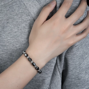 Detail of gray hematite and silver textured beads on a men's beaded bracelet