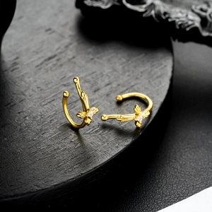 Detailed view of two gold-plated U-shaped ear cuffs featuring sparkling zircon floral motifs