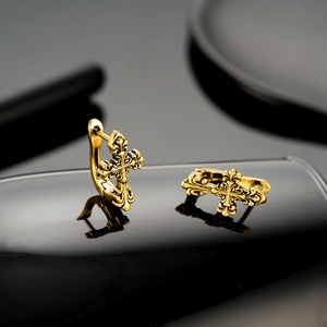 Boucles d'oreilles croix dorées vintage avec motif fleur de lys sur fond noir chic