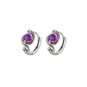 Dettaglio macro di orecchini a cerchio a serpente argento con scaglie e perle viola