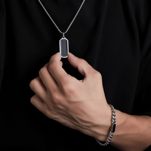 Primo piano del bracciale a catena cubana e della collana con ciondolo in acciaio da uomo