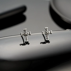 Retro cross stud earrings with vintage silver finish and knot texture on black background