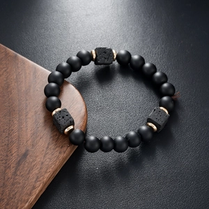 Close-up of matte black beads and square volcanic stone bracelet with gold accents