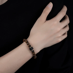 Tiger eye and volcanic stone beaded bracelet with gold spacers on male wrist