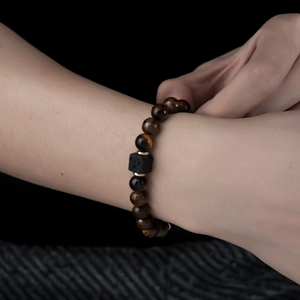 Detail shot of tiger eye beaded bracelet with volcanic stone accent on a textured base