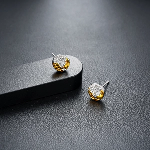 Macro shot of silver and gold mixed metal stud earrings with textured hammered finish