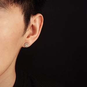 Macro shot of men's hexagonal sun stud earring with inlaid gemstone on ear