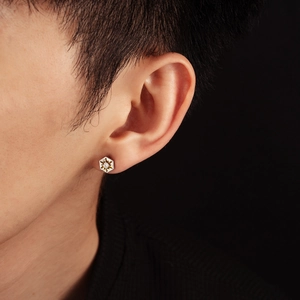 Macro shot of a silver hexagonal stud earring with zircon inlay worn by a person