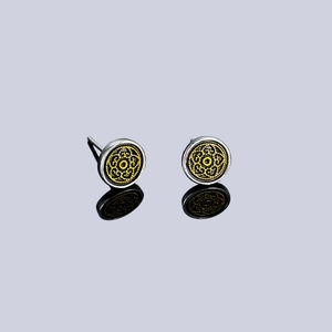 Close-up of silver earrings featuring intricate yellow floral filigree patterns