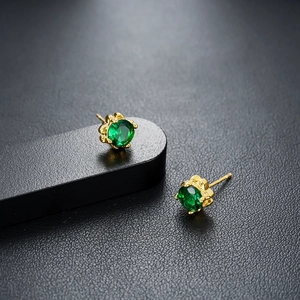 Macro shot of 18K gold plated studs featuring round emerald green cubic zirconia settings