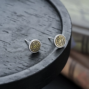 Macro detail of retro round metal earrings with silver polish and gold filigree center