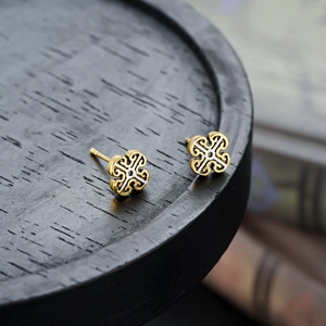 Retro two-tone clover stud earrings with vintage metal texture on black wood base