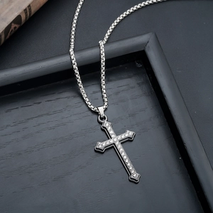 Close-up of silver cross pendant with inlaid white cubic zirconia on a box chain