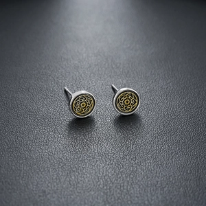 Detailed close-up of retro silver earrings with golden intricate floral pattern