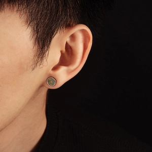 Close-up of retro silver stud earring with golden mandala pattern on male model