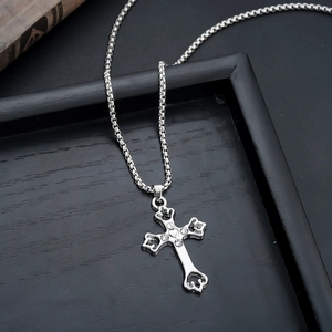 Detailed view of silver cross pendant with inlaid crystals and a heart-shaped center