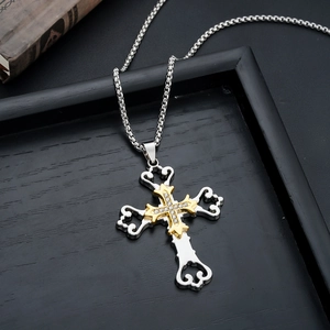 Close-up of two-tone cross necklace with white rhinestones and gothic filigree detail