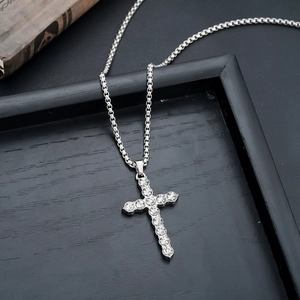 Detail of silver cross necklace with clear crystals on retro book and black leather