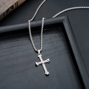Detailed shot of gothic silver cross pendant with pink heart gemstone and bone design