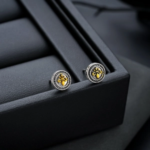 Macro shot of vintage fleur-de-lis stud earrings in oxidized silver and gold finish