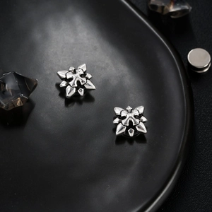 Makroaufnahme von Vintage Magnetohrclips aus Silber im Gothic-Stil mit Stern-Kreuz-Muster