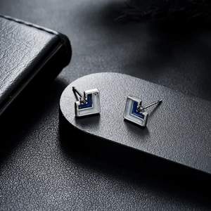 Detail of geometric L-shaped stud earrings with blue and white enamel on silver metal