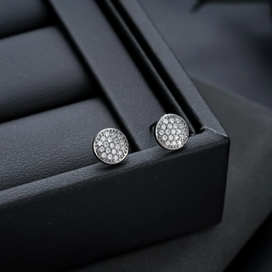 Gros plan de boucles d'oreilles rondes en argent serties de zircons brillants pavés