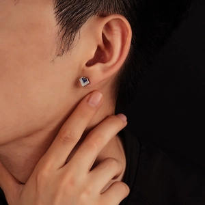 Detail of a men's silver geometric V-shape stud earring with blue and white enamel inlay